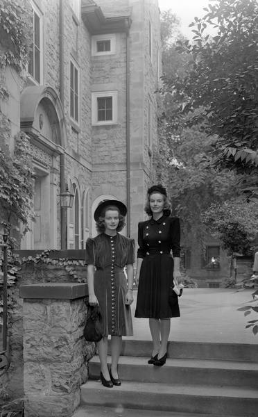 Two Manchester's Department Store coed models, wearing dresses, hats and purses, posing in front of Langdon Hall, 633 Langdon Street.