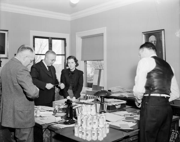 Four CUNA (Credit Union National Association) officers, including Roy Bergengren, open can banks in the Credit Union National Association office at the Raiffeisen House, 142 East Gilman Street.
