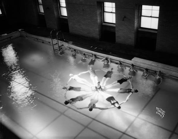 Elevated view of University of Wisconsin-Madison Dolphin Club women in the Lathrop swimming pool in a synchronized swimming formation.