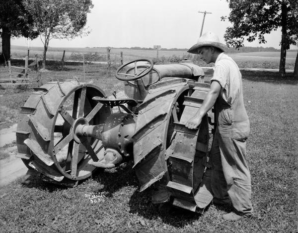 Man attaches extra rims onto a Fordson tractor.