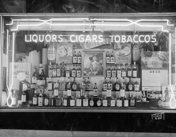 Window display with neon sign at Madison Liquor and Cigar Store, 109 Monona Avenue, featuring Calvert liquor.