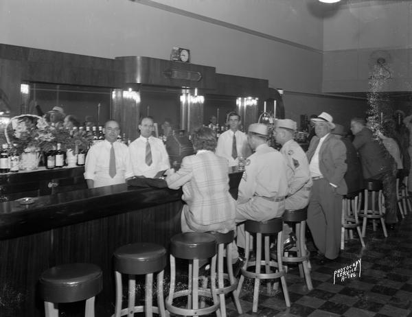 Interior of Rex Bar, 546 West Washington Avenue with three bartenders and patrons, including two men in uniform sitting at the bar.