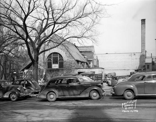 First Unitarian Society Meeting House, 125 Wisconsin Avenue, being razed by Arneson Wrecking Company. View is from Wisconsin Avenue. On the left is the education building of the First Methodist Church, 14 East Dayton Street. Automobiles are parked on the street.