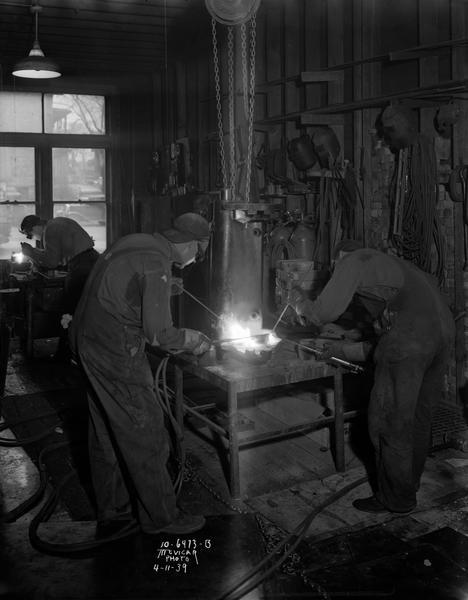 Two welders in welding shop at Howard Welding Company, located at 319 E. Wilson Street.