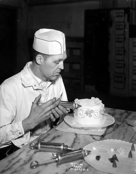 Man icing a small cake, taken for Kennedy Dairy Co.