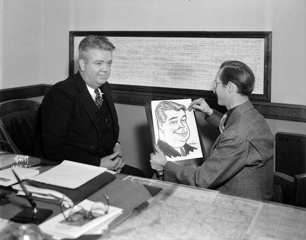 Adjutant General Ralph Immell, sitting at his desk, having his face drawn by cartoonist, Hy Vogel.