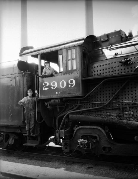 Railroad Week publicity photograph steam locomotive, with a girl in the cab and a railroad worker standing on the engine steps.