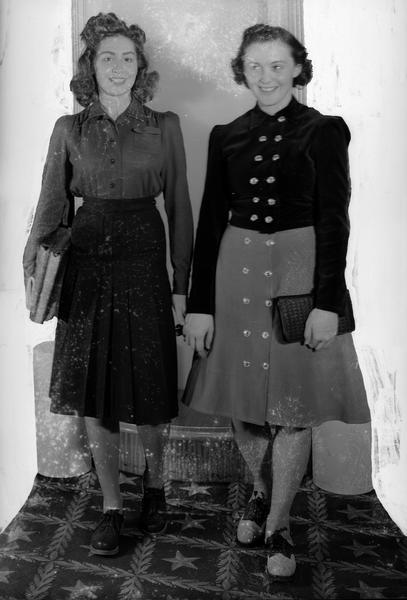 Female clothing models, Beverly Muenchow and Eileen Regan, at the Darling Shop, located at 9 East Main Street. They are wearing skirts with blouses and saddle shoes.