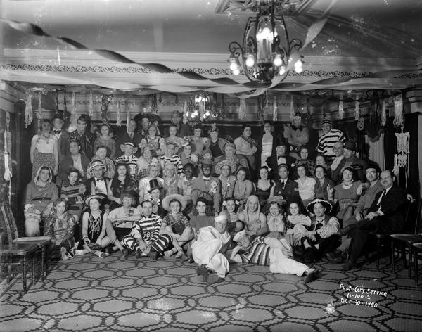 Group portrait of adults in Halloween costumes in the Colonial Room at the Loraine Hotel.