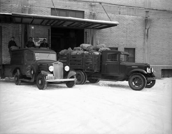 Three men loading two L.L. Olds Seed Co. trucks with out-going mail, at 722 Williamson Street.