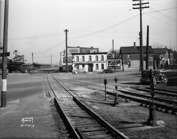 Chicago & Northwestern Railroad tracks, looking east at the crossing of S. Blair Street, King Street, E. Wilson Street, and Williamson Street. Included in the view is the Wilmont Baker Tavern at 601 E. Wilson Street, and other buildings on E. Wilson Street and Williamson Street.