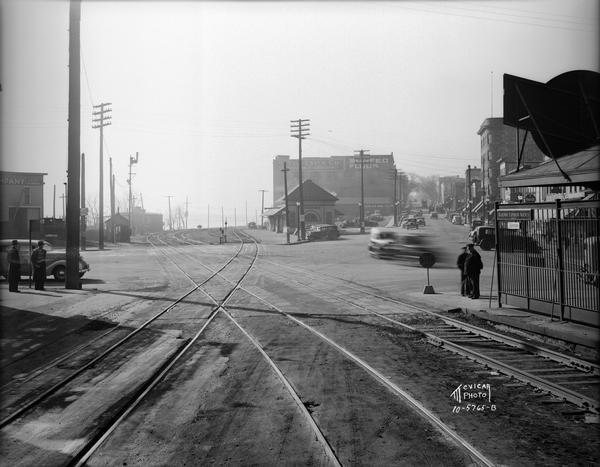 Chicago & Northwestern Railroad tracks, looking west at the crossing of S. Blair Street, King Street, E. Wilson Street, and Williamson Street. Shows Chicago, Milwaukee, St, Paul & Pacific Railroad depot, 501 E. Wilson Street and other businesses in the 500 block of E. Wilson Street.