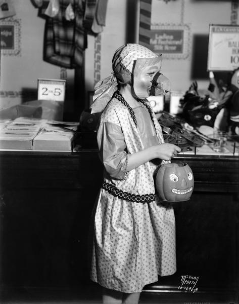 Esther Johnson wearing a Halloween costume and big-nosed mask, and holding the Jack-o-Lantern that for the <i>Capital Times</i> "Schnozzle" parade in honor of Jimmy Durante's movie "The Phantom President."