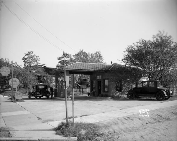 Man filling automobile at Shell Service Station, located at 2643 University Avenue at Farley Avenue. Another man is working on an automobile on a lift outside the station.