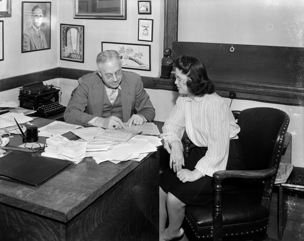 CUNA (Credit Union National Association) Managing Director, Roy F. Bergengren, sitting at desk, talking to female employee.