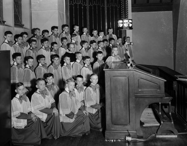 Blessed Sacrament Catholic Church's boys choir grouped in front of the organ, with The Reverend James A. McInerney (Father Mac) in their midst. The church is located at 2119 Rowley Avenue.