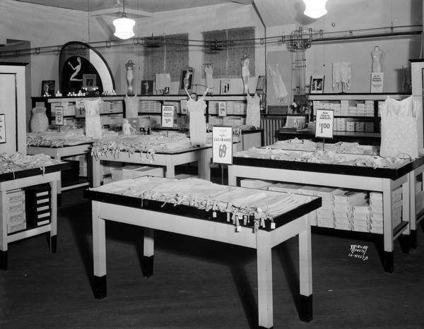 Hill's Dry Goods Store, corset department. There are tables piled with various styles of foundation garments.