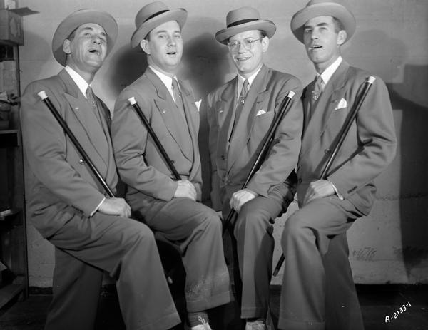 Publicity portrait of "The Cardinals" barbershop quartet, posing with one foot on a riser. From left to right are Jerry Ripp, Vaughn Liscum, Phil Davies and Joe Ripp.