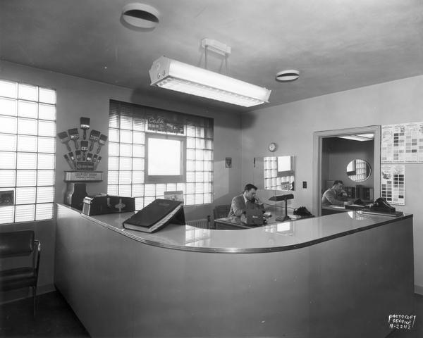 Interior of Pittsburgh Plate Glass Company office, 2422 Pennsylvania Avenue. Two men are sitting at desks.