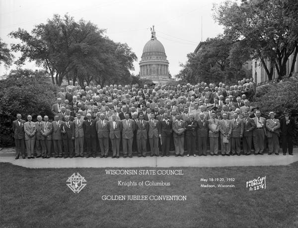 Group portrait of Knights of Columbus Golden Jubilee Convention, taken at the foot of Monona Avenue (Martin Luther King Jr. Boulevard), with the Wisconsin State Capitol in the background.