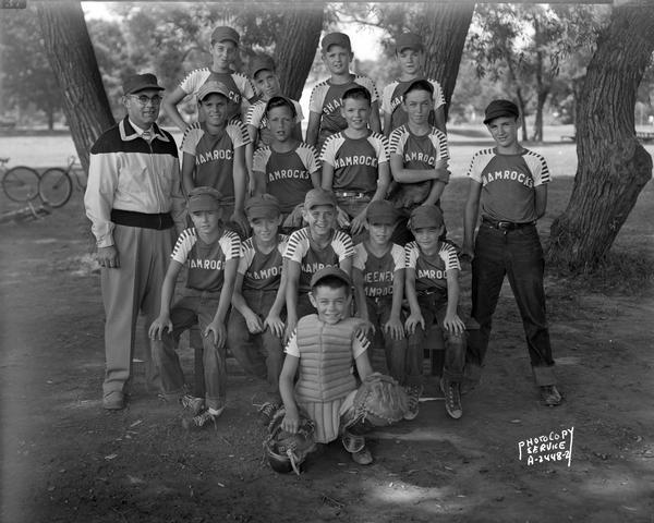 Group portrait of the Shamrock youth baseball team. There are 15 boys in Shamrock t-shirts, and one coach.