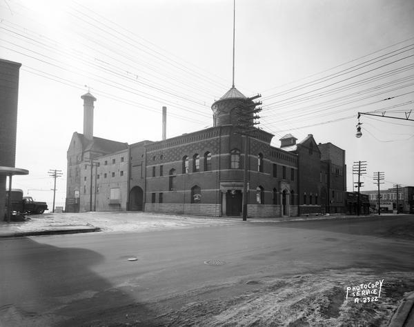 Fauerbach Brewery, 651-653 Williamson Street, at the corner of South Blount Street and Williamson Street. The view includes R.J. Olson Glass Co., 625 Williamson Street; Midway Super Service Sinclair Gas Station, 631 Williamson Street; and Crane Plumbing, 641 Williamson Street. Lake Monona is in the background.