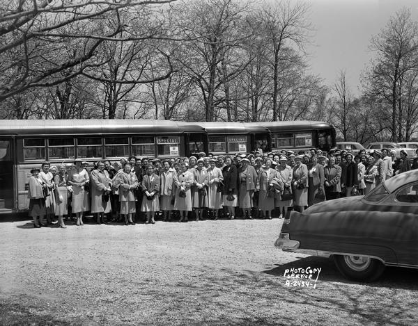 Large group of Knights of Columbus women, standing in front of buses made to look like railroad cars. They are returning from a convention held in Racine.