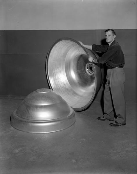 Man holding up one of two large W.R. Carnes Company air diffuser shells to show their size.