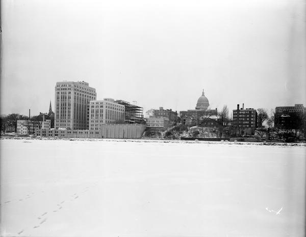 Downtown Madison lakeshore taken from Lake Monona in line with South Pinckney Street. Includes St. Raphael's steeple, 1 West Wilson Street state office building, the Wisconsin State Capitol building, the Madison Club, the Belleview apartment building, and the City-County building under construction.