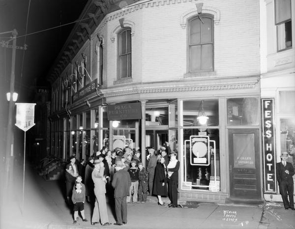 Crowd in front of Praga Furniture store, 203-207 King Street, at 1st Anniversary celebration. The Fess Hotel sign is along a doorway on the right.