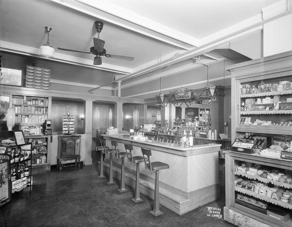 New soda fountain counter at Kleinheinz Pharmacy, located at 714 South Park Street. The view includes shelves and merchandise.