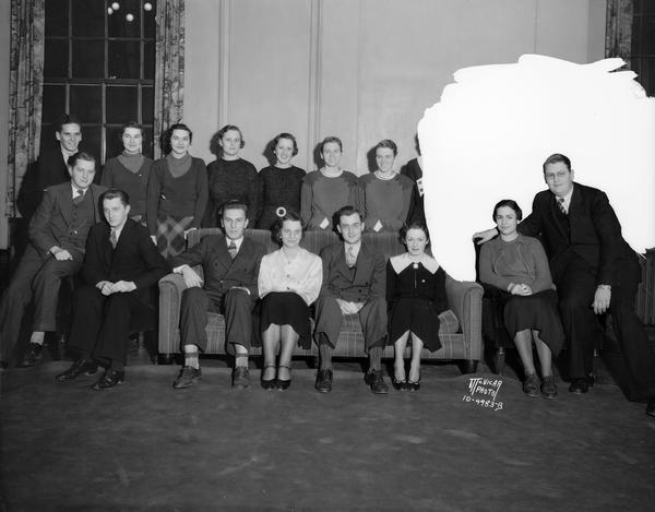 Group portrait of nine pairs of twins, students at the University of Wisconsin. Rear row, l to r: Rudy Custer, Elizabeth & Mary Rhodes, Lucille & Betty Ransom, Jane & Elenor Bond, Barbara & Beatrice Nicoll, and Frank Custer. Sitting at the left are Lloyd & Floyd Paust. At the right are Arlene & Howard Wessel, On the divan, l to r are: Bruce & Bonnie Beilfus, and William & Lydia Keown.
