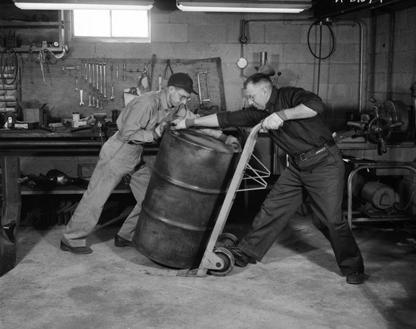 Two men moving an oil barrel at Coolant Equipment Corporation.