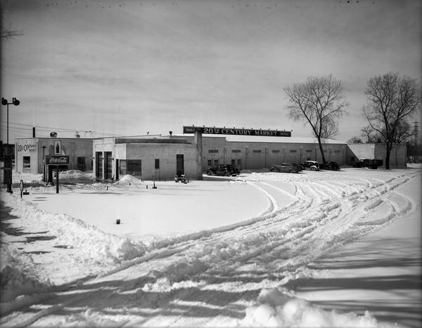 Winter scene with the 20th Century Market, located at 1860 East Washington Avenue. There is snow on the ground. The Lee Tires garage is next door.