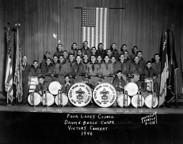 Four Lakes Council Boy Scout Drum & Bugle Corps on stage at Central High School, in uniforms with instruments and flags, for Victory concert.