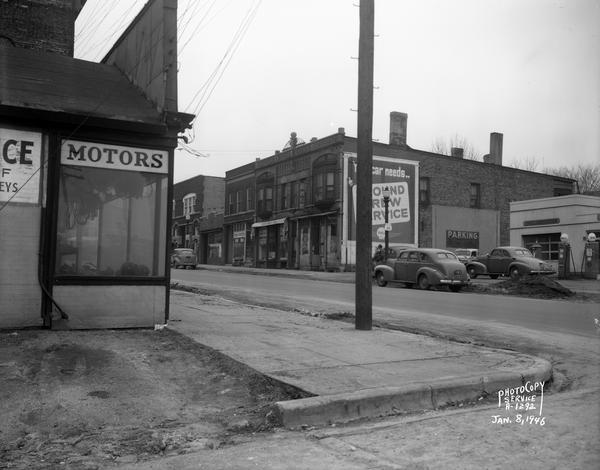 East Wilson Street scene at the center of South Hancock looking West, taken at site of Reynolds Bus accident. Businesses include Shell Service at 324 East Wilson Street, R & R Cafe at 316 East Wilson Street, Madison Watch Shop at 314 East Wilson Street, Capitol City Furniture Co. at 310 East Wilson Street, Johnson Maytag Company at 306 East Wilson Street, and Electric Motor Service at 323 East Wilson Street.