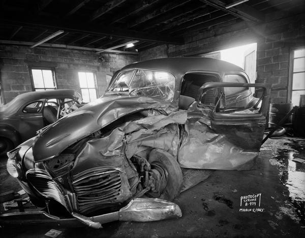 Damaged Plymouth automobile (owned by Raymond White) in O.C. Harris Co. garage on Highways 12-18-51.