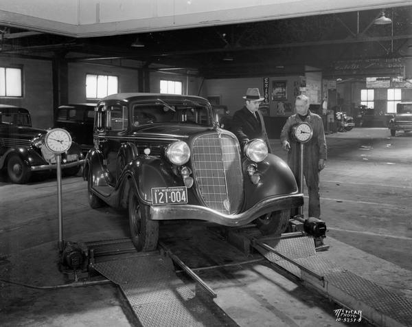 Two men test the front wheels of an automobile at Eichman Garage, located at 1307-09 Williamson Street.