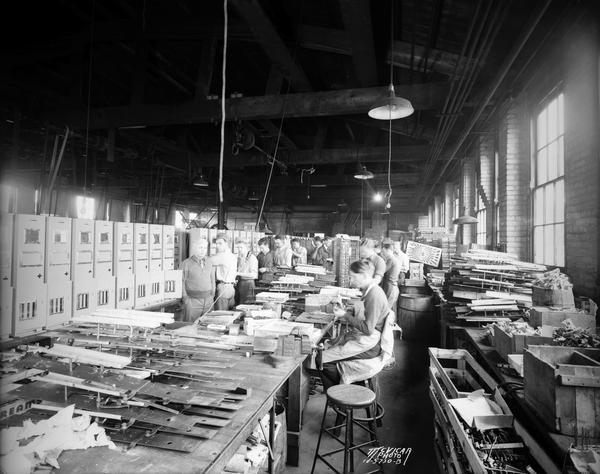 Interior of the Rushour Manufacturing Company Inc., 2070 Helena Street. Men are working on the vending machine assembly line.