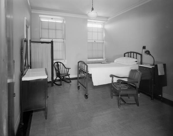 Wisconsin General Hospital room with bed, dresser, bedside stand with lamp, two chairs and a free-standing screen, 1300 University Avenue.