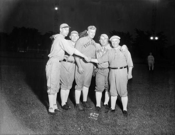 Five legislators dressed in baseball uniforms shaking hands before a baseball game at Breese Stevens Field. L to R: Senator Sherman W. Wade, Antigo; Joseph McDermid, Ladysmith; Hugh A. Harper, Lancaster; Morley G. Kelly, Fond du Lac; Assemblyman Thomas H. Caffrey, Milwaukee.