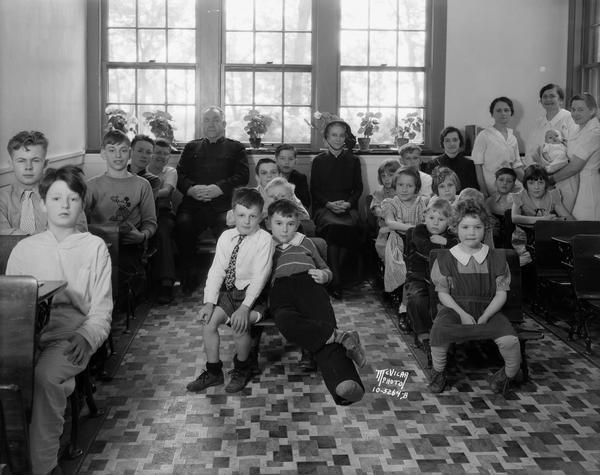 Group portrait of children with tuberculosis and their attendants, and with a man and woman in Salvation Army uniforms, sitting in a classroom at the Morningside Sanitorium, 300 Femrite Drive.
