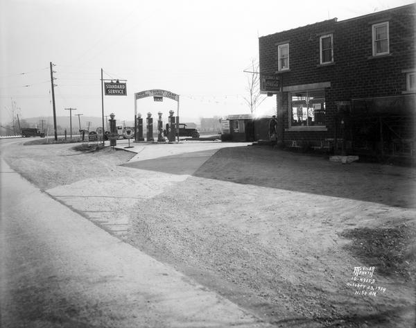 Hope Corners with sign for "Hope Tourist Camp: Groceries, Cabins, Garage" featuring Standard Service, Red Crown Gasoline, Quaker State Oil & Penzoil. 3737 Buckeye Road (Highway AB) looking east down Femrite Road at Hope Corners.