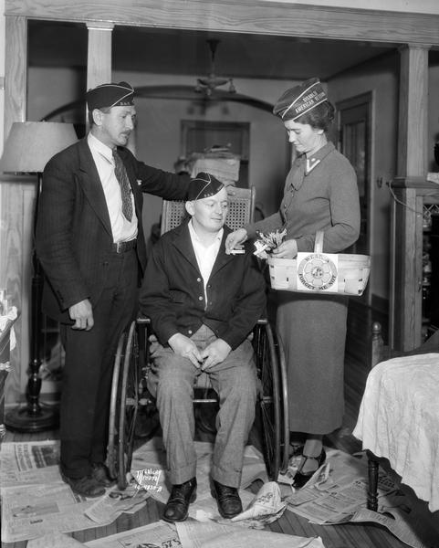 Howard Miner, disabled World War I veteran, receiving Forget-me-not flower from Florence Palz, ladies auxiliary chairman, marking the opening of the forget-me-not campaign of the Disabled American Veterans. Standing at the left is R.A. Kindschi, chairman of the annual campaign.