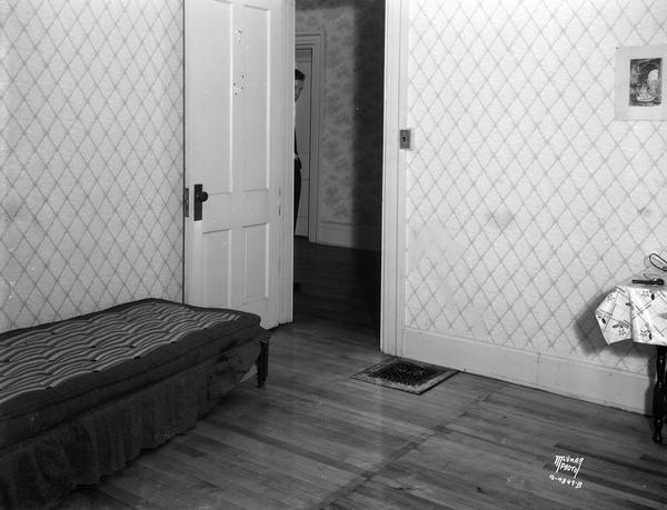 Doorway and bed in a room on 521 North Henry Street where a murder-suicide occurred. Adele Burnton was murdered by Harold Kotvis, who then committed suicide. A man is standing just behind the open doorway on the left.