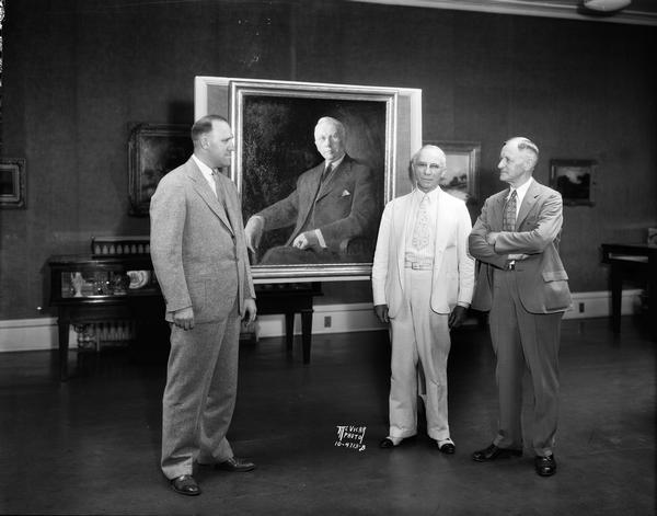 W.A. Devine, Madison postmaster for 24 years, with his portrait, painted by Arthur N. Colt, a Madison artist, at State Historical Society, 816 State Street. Shown with him: (Left) Milton Findorff, President of Association of Commerce, (Right) Joseph Schafer, Superintendent of Historical Society.