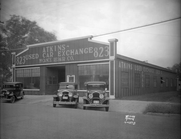 Three automobiles are parked in front of Atkins Used Car Exchange and McCance Repair Co., 823 E. Mifflin Street. Trachte building.