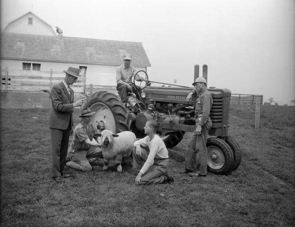 William F. Renk pointing to his son Robert Renk (sitting on John Deere tractor with Firestone Tires) and Walter Renk, leaning on the tractor. Another son, Wilbur Renk, and grandson John Renk are kneeling in front of tractor and holding a sheep. The farm is located 1000 Wilburn Road.  The Renks raised seed corn and sheep. Renk sheep were famous throughout the United States for their show winnings and for their blood lines.