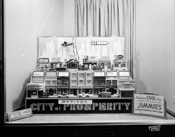 Animated display window at Master Furriers, 11 West Main Street, "Madison City of Prosperity," display of miniature storefronts with Madison merchants' store names and cars and trucks traveling in front and an airplane in the sky, "Madison's Cool Idea, 11 Noon to Mid-night, plus Jimmie's Celebrated Restaurant & Cocktail Lounge."
