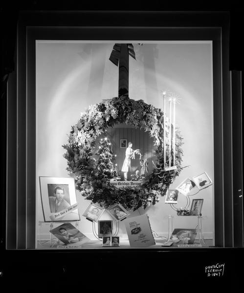 H.S. Manchester Inc., 2 East Mifflin Street, photo studio display window, featuring large holly wreath with center depicting Christmas morning scene and portrait photos of children. "Manchester's celebrates the reopening of its portrait studio ... 'Uncle Dick' famous for his portrait studies of children is here this week only."